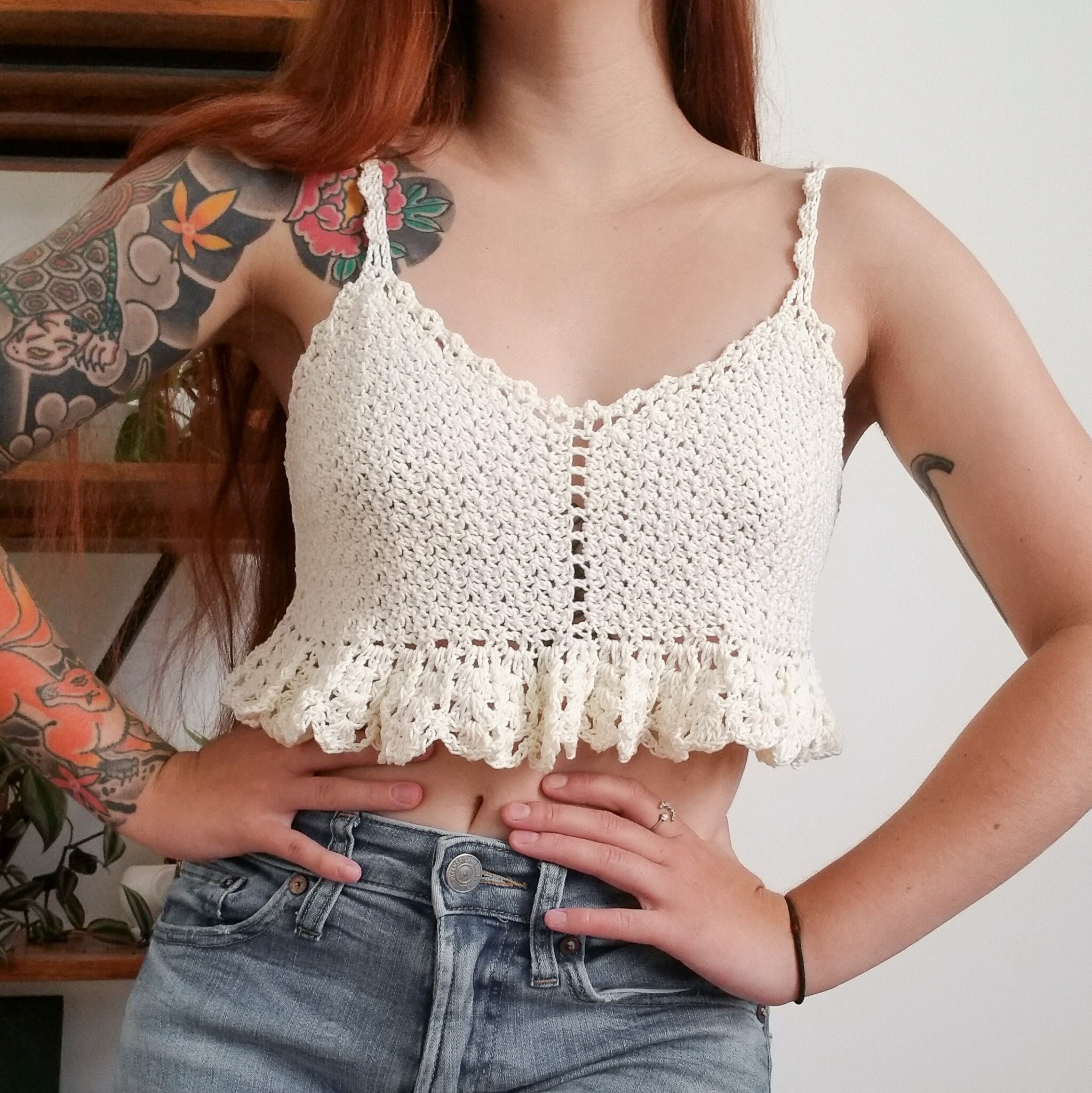 Hands using a needle to weave in ends of a crochet babydoll dress